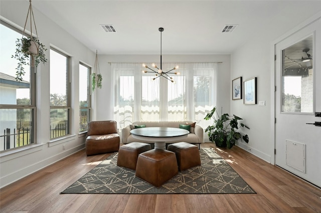 sunroom / solarium featuring ceiling fan with notable chandelier and a healthy amount of sunlight