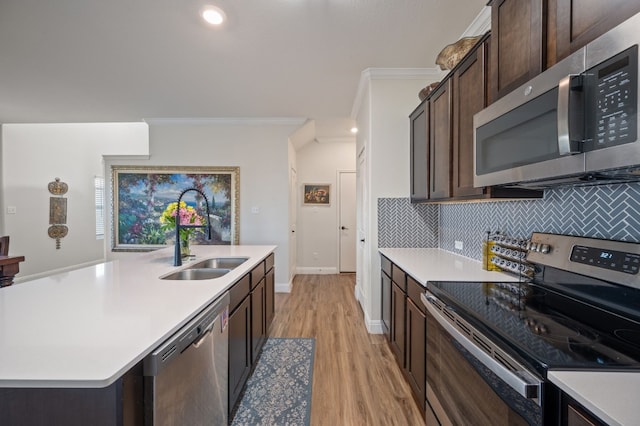 kitchen featuring a center island with sink, sink, tasteful backsplash, light hardwood / wood-style floors, and stainless steel appliances