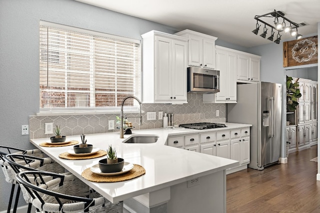 kitchen featuring sink, a breakfast bar area, dark hardwood / wood-style flooring, white cabinetry, and stainless steel appliances