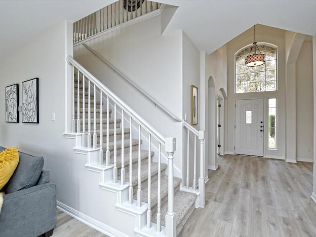 entryway with light wood-type flooring and a towering ceiling