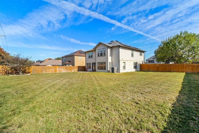 rear view of property with central AC unit and a yard