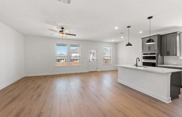 217 Canyoncrest Way, Liberty Hill, TX 78642 - kitchen featuring stainless steel double oven, gray cabinetry, light countertops, a ceiling fan, and light wood-type flooring