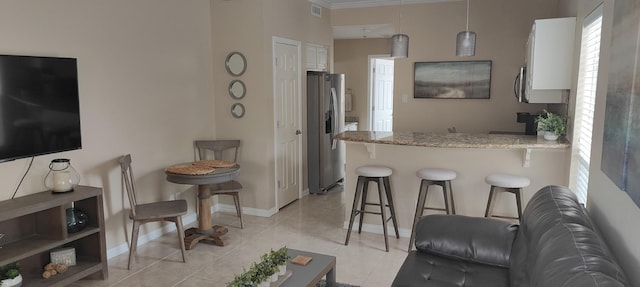 kitchen with white cabinets, a kitchen breakfast bar, pendant lighting, and stainless steel fridge with ice dispenser