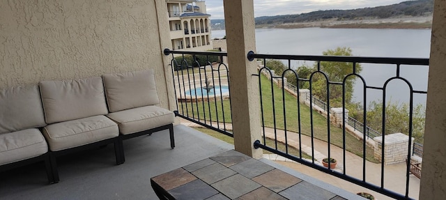 balcony with an outdoor living space and a water view