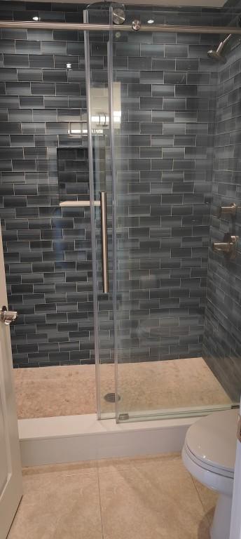 bathroom featuring tile patterned flooring, an enclosed shower, and toilet