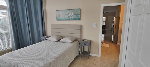 bedroom featuring stainless steel refrigerator and light tile patterned flooring