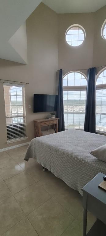 tiled bedroom with multiple windows and high vaulted ceiling