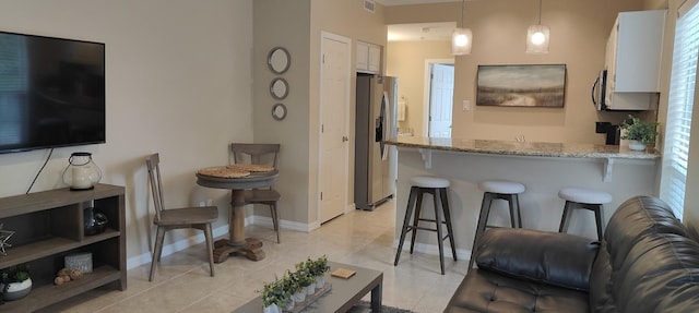 kitchen with white cabinets, pendant lighting, a breakfast bar, and stainless steel fridge with ice dispenser