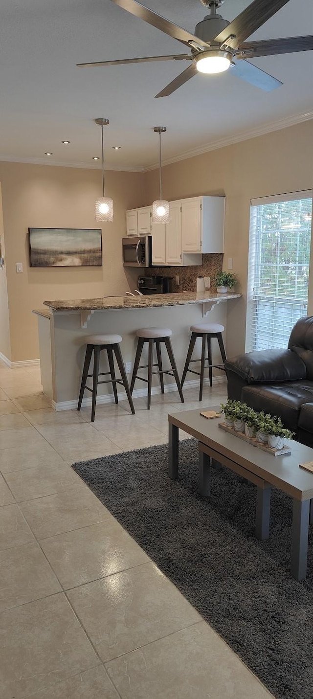 interior space featuring crown molding, ceiling fan, and light tile patterned floors