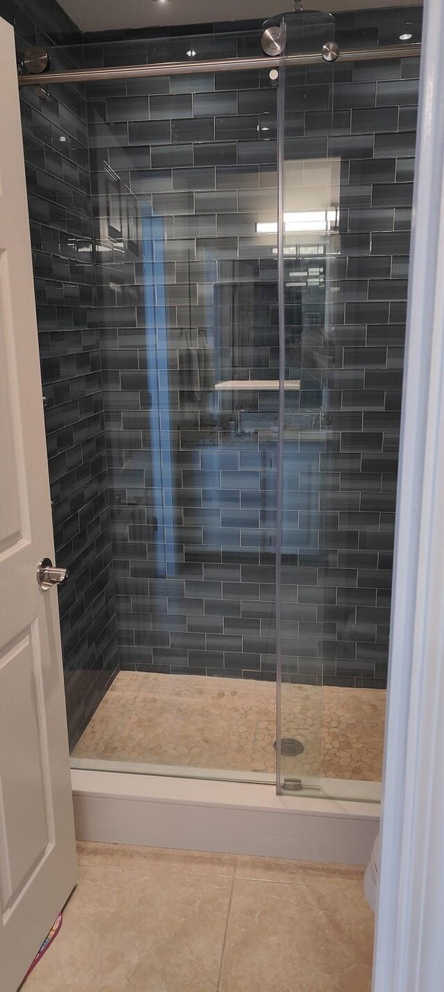 bathroom with a shower with shower door and tile patterned floors