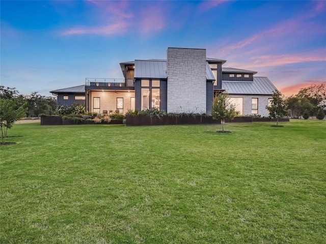 back house at dusk featuring a lawn