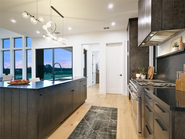 kitchen featuring high end range, light wood-type flooring, hanging light fixtures, and sink