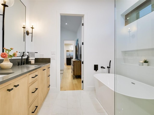 bathroom featuring vanity, a tub, and vaulted ceiling