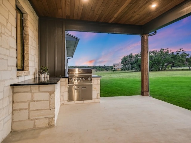 patio terrace at dusk with a lawn, area for grilling, and grilling area