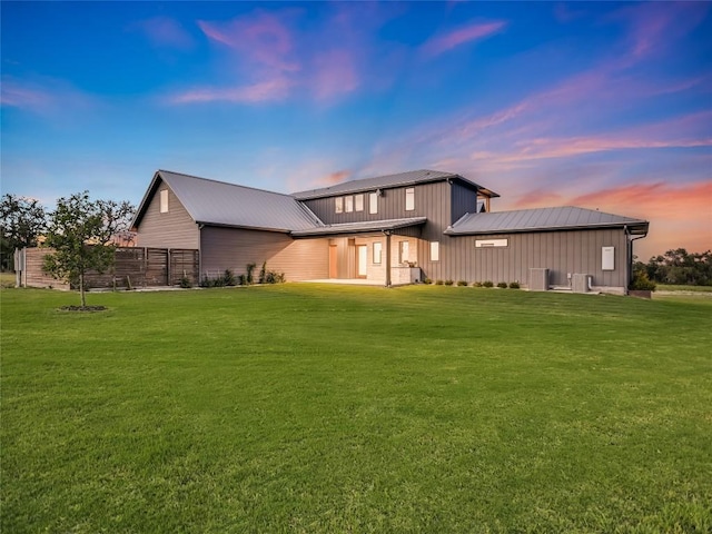 back house at dusk with a yard and central AC