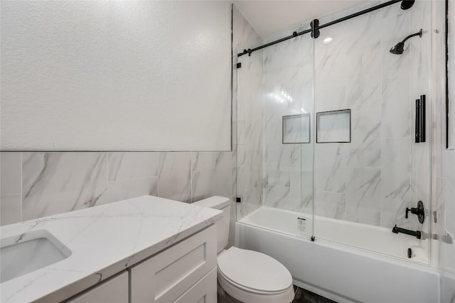 full bathroom with shower / bath combination with glass door, vanity, tile walls, and toilet