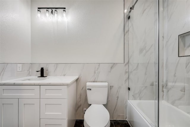 full bathroom featuring toilet, vanity, tile walls, and tiled shower / bath