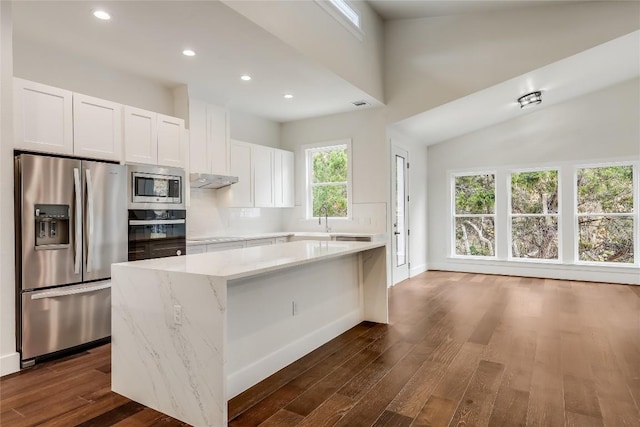 kitchen with white cabinets, light stone counters, dark wood-type flooring, and appliances with stainless steel finishes