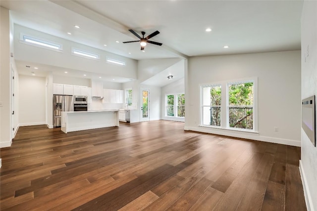 unfurnished living room featuring ceiling fan, high vaulted ceiling, and dark wood-type flooring