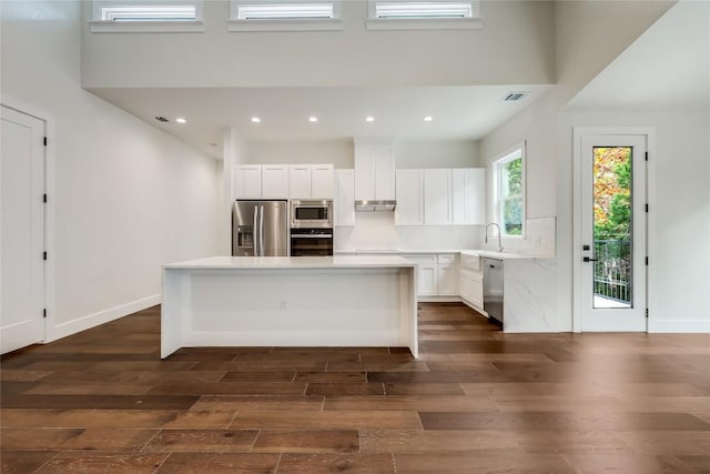 kitchen with a center island, dark hardwood / wood-style flooring, stainless steel appliances, and white cabinetry