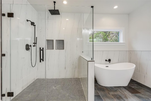 bathroom with hardwood / wood-style floors, plus walk in shower, and tile walls