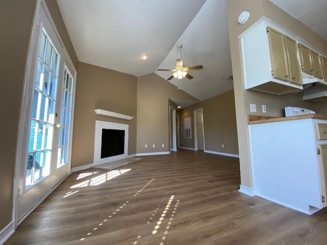 1005 N Lbj Dr Unit A-5, San Marcos, TX 78666 - unfurnished living room with vaulted ceiling, a ceiling fan, wood finished floors, baseboards, and a fireplace with flush hearth