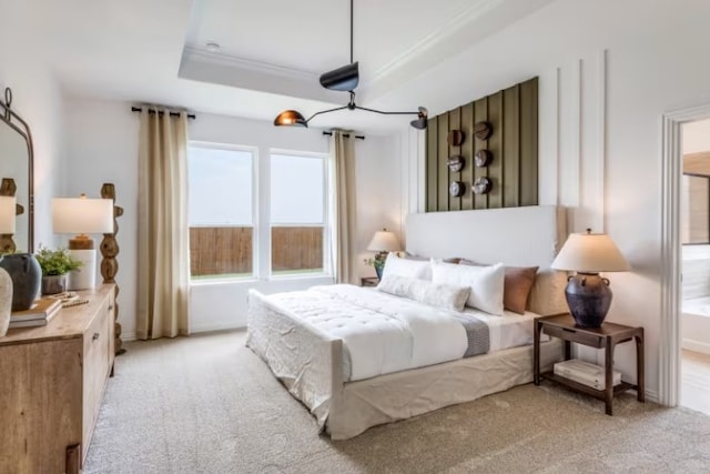 bedroom with a raised ceiling and light colored carpet