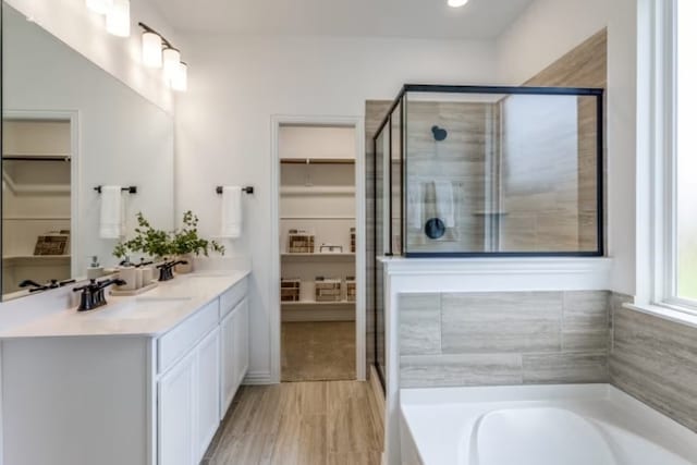 bathroom featuring plus walk in shower, wood-type flooring, and vanity