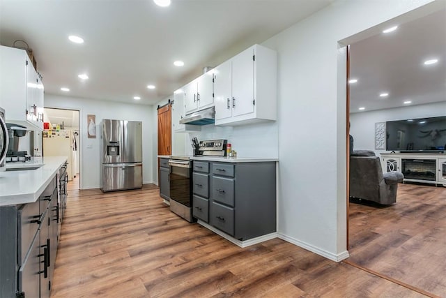 kitchen with white cabinets, appliances with stainless steel finishes, a barn door, and gray cabinets