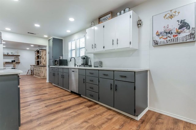 kitchen featuring gray cabinetry, white cabinets, light wood-type flooring, and stainless steel appliances