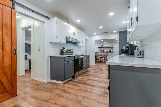 kitchen featuring stainless steel electric stove, gray cabinets, a barn door, light hardwood / wood-style floors, and white cabinetry