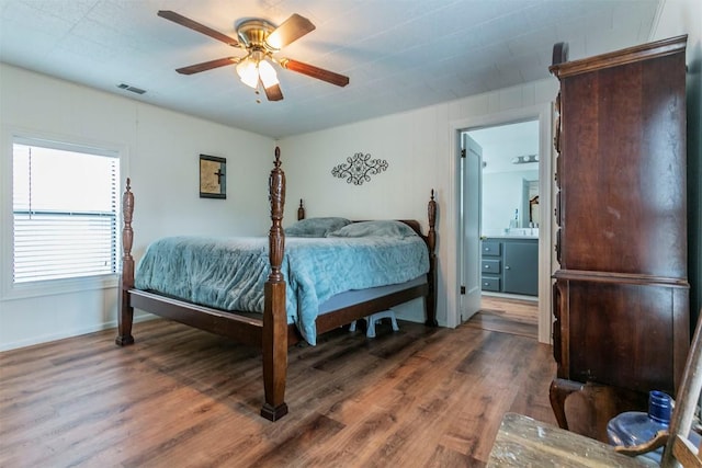 bedroom with connected bathroom, ceiling fan, and dark wood-type flooring