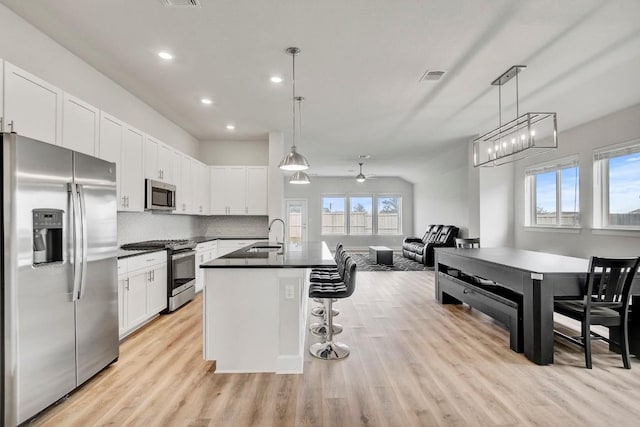 kitchen with light hardwood / wood-style floors, white cabinetry, hanging light fixtures, and appliances with stainless steel finishes