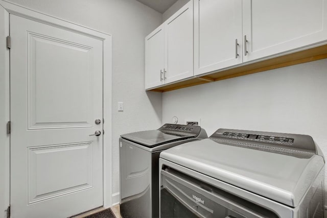 laundry room with separate washer and dryer and cabinets