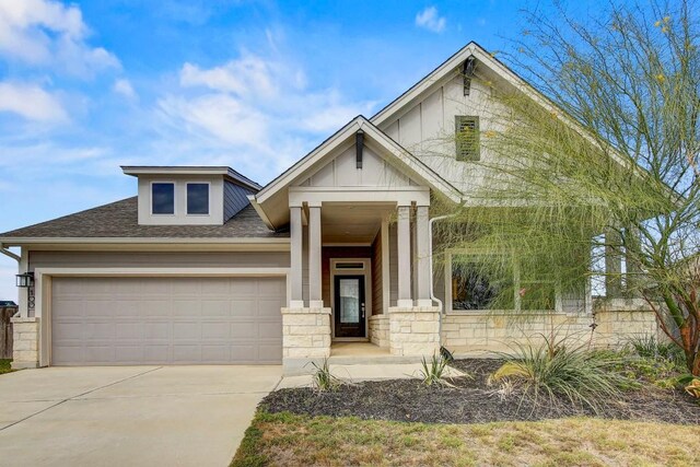 100 Patrick Herndon Dr, Bastrop, TX 78602 - view of front facade featuring a garage, driveway, roof with shingles, board and batten siding, and stone siding