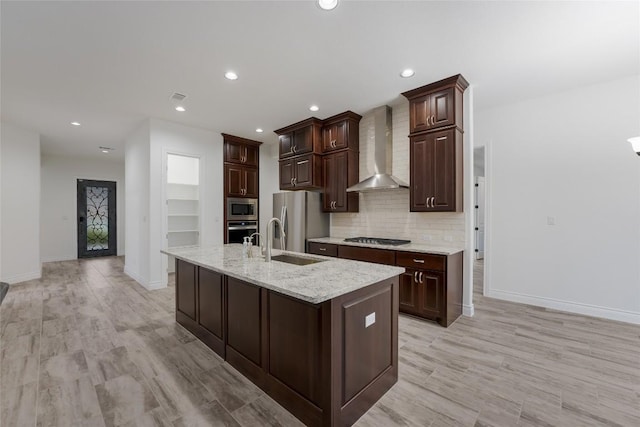 kitchen featuring sink, wall chimney exhaust hood, light hardwood / wood-style floors, dark brown cabinetry, and stainless steel appliances