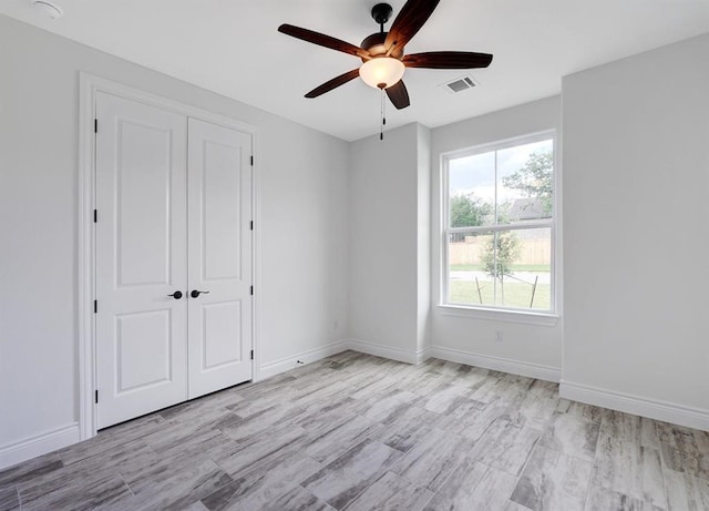 unfurnished bedroom with ceiling fan, light hardwood / wood-style flooring, and a closet