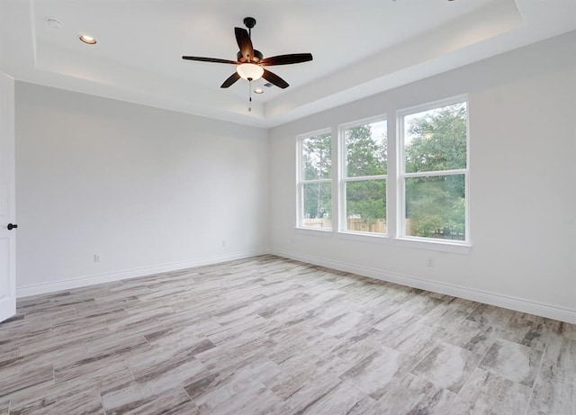 spare room featuring ceiling fan, a healthy amount of sunlight, and a raised ceiling