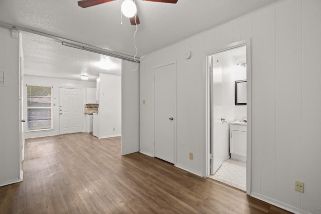 interior space featuring ensuite bathroom, hardwood / wood-style floors, ceiling fan, and a textured ceiling