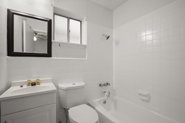 full bathroom featuring ceiling fan, tiled shower / bath combo, toilet, vanity, and tile walls