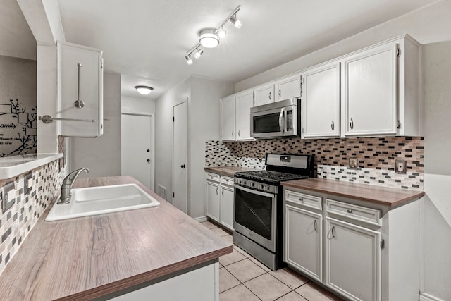 kitchen featuring white cabinets, appliances with stainless steel finishes, decorative backsplash, and sink