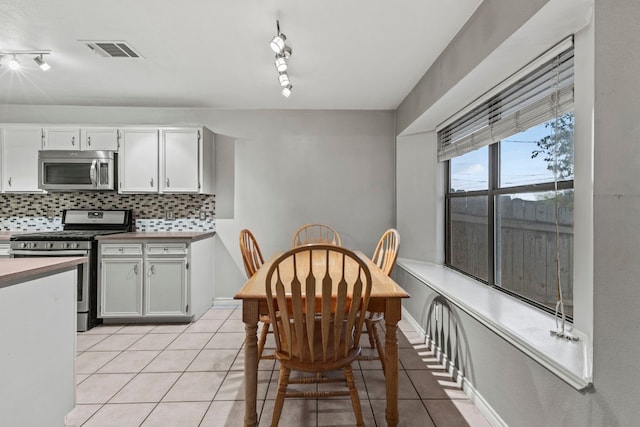 kitchen with white cabinetry, backsplash, track lighting, light tile patterned flooring, and appliances with stainless steel finishes