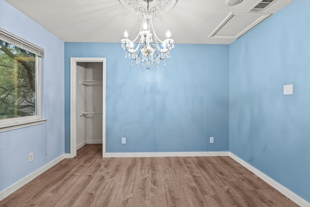 empty room with a chandelier and light hardwood / wood-style floors