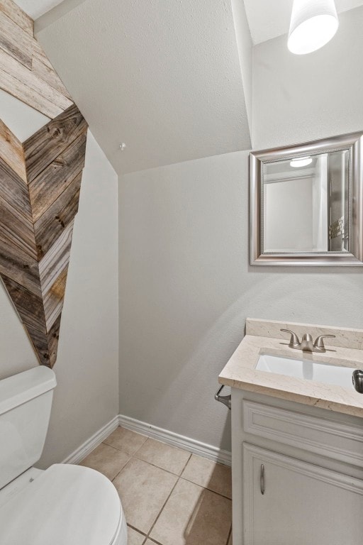 bathroom with tile patterned floors, vanity, lofted ceiling, and toilet