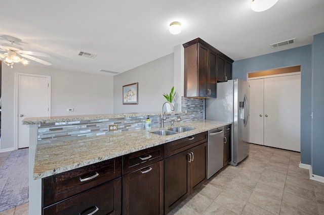 kitchen featuring appliances with stainless steel finishes, backsplash, light stone counters, and sink