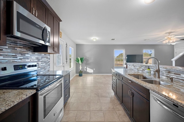 kitchen with appliances with stainless steel finishes, tasteful backsplash, light stone counters, and sink