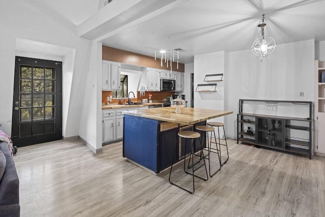 kitchen featuring white cabinetry, sink, stainless steel appliances, pendant lighting, and a kitchen island