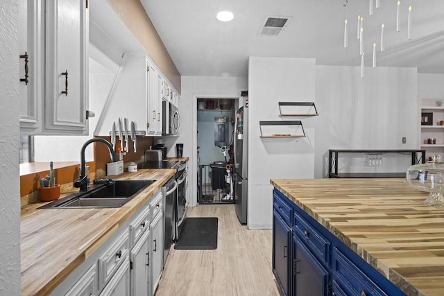 kitchen with blue cabinetry, light hardwood / wood-style flooring, wooden counters, and sink