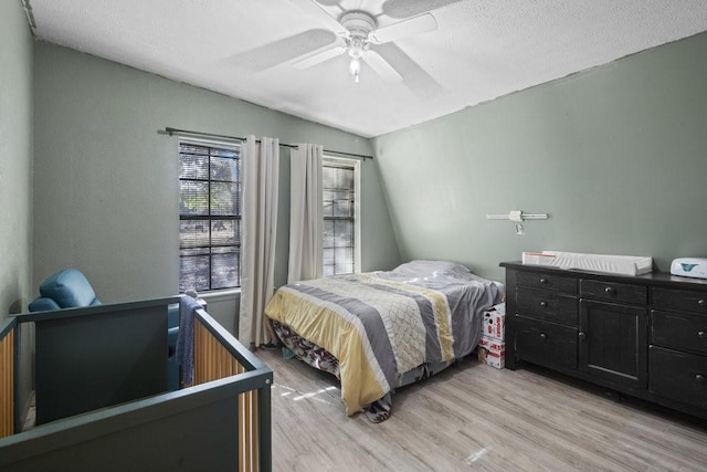 bedroom with a textured ceiling, light hardwood / wood-style floors, vaulted ceiling, and ceiling fan