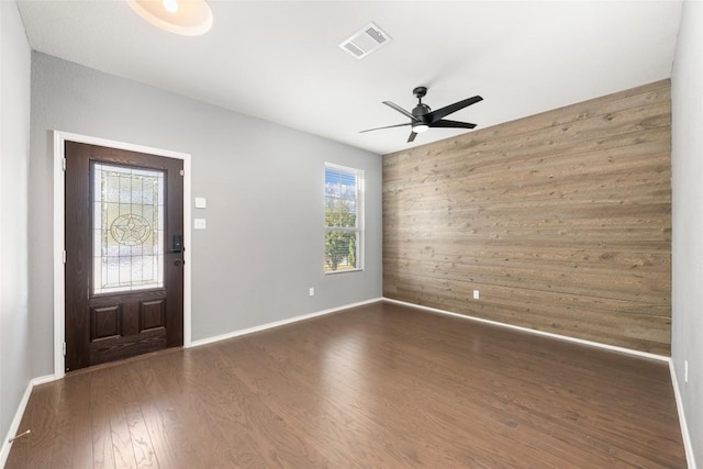 entryway with wood walls, ceiling fan, and dark wood-type flooring